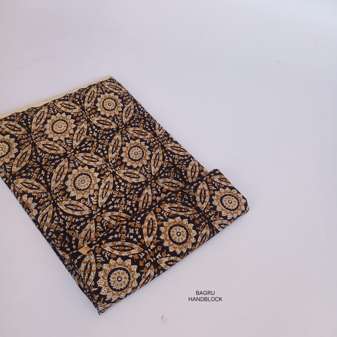 Intricate black jaal Bagru handblock printed cotton fabric, naturally dyed and artisan-produced for boutique collections.