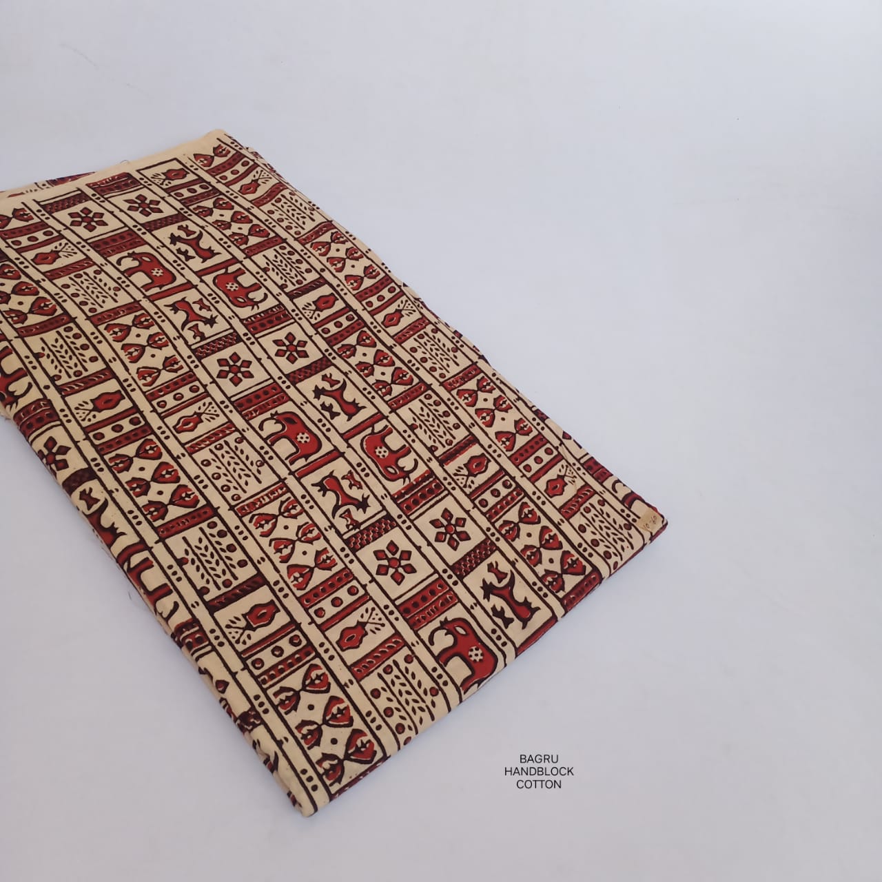 Cream and red Bagru handblock printed pure cotton fabric with Warli tribal art, handcrafted and sustainable wholesale textile.