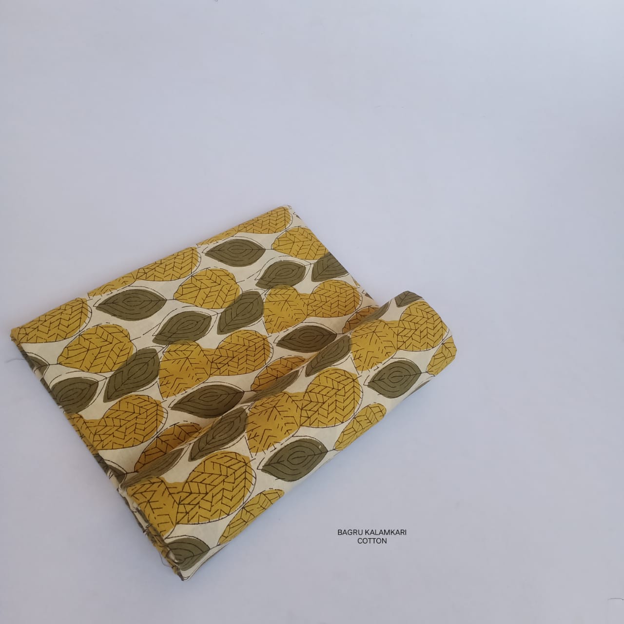 Mustard Bagru handblock printed pure cotton fabric with leaf motifs, sustainable and artisan-crafted for Fabtexs wholesale fabric range.