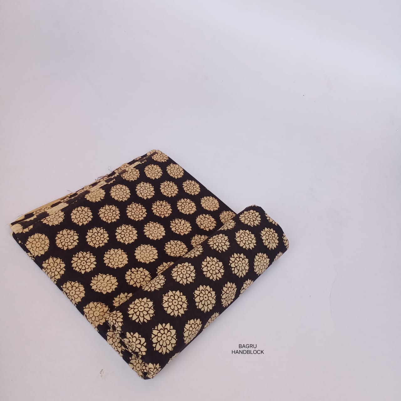Bagru handblock printed cotton fabric in black with floral designs, crafted by local artisans for Fabtex wholesale.